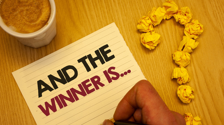 Question mark with "an the winner is" written on paper