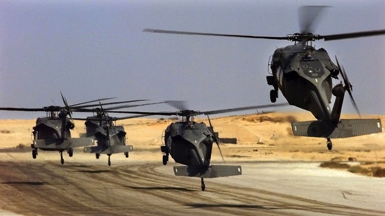 Several Army helicopters landing in desert