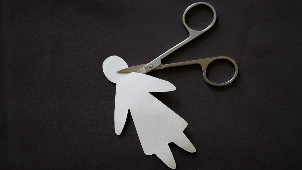 Scissors cutting paper doll's neck