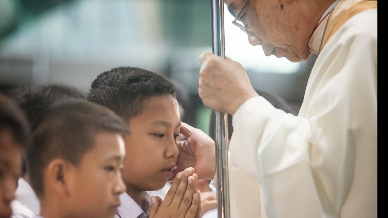 Priest blessing boy in seminary