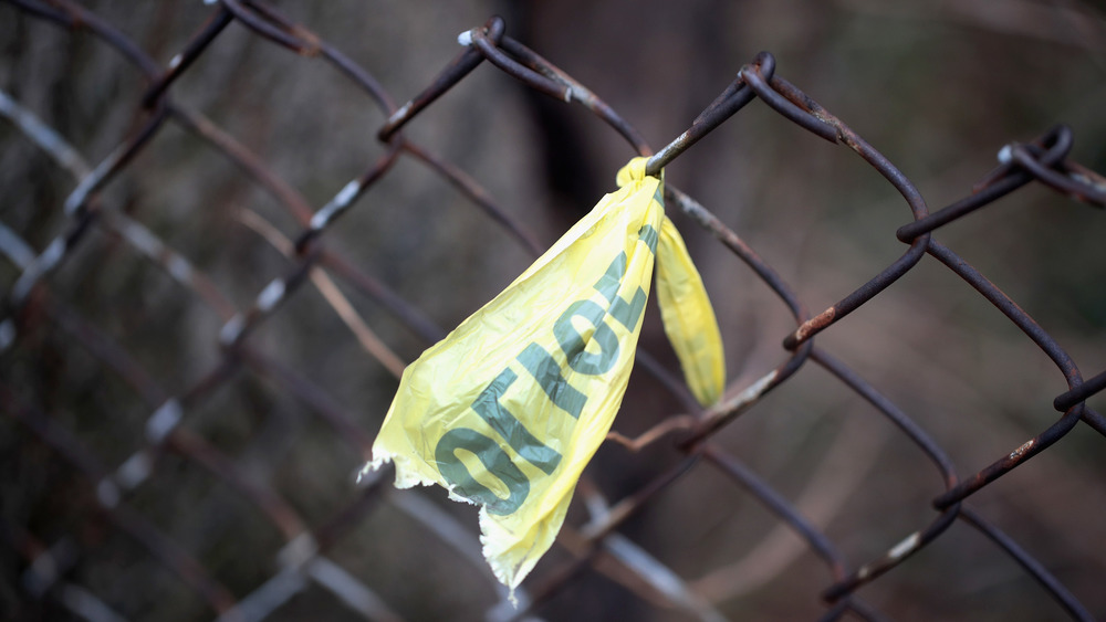 Crime scene tape is knotted on a wire fence