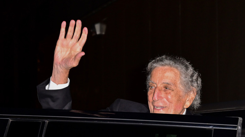 Tony Bennett waves out of a car