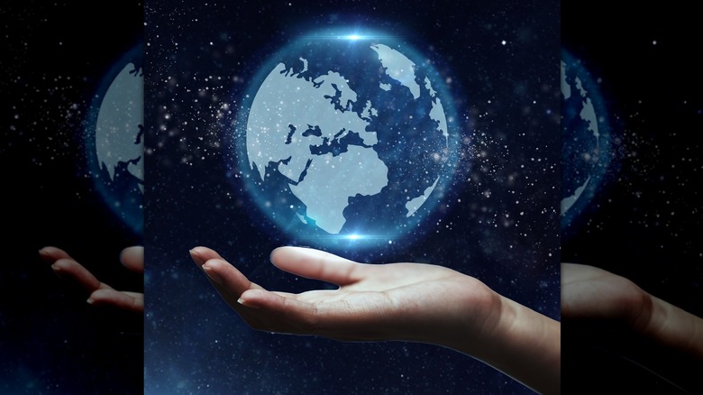 Hand holds Earth and stars