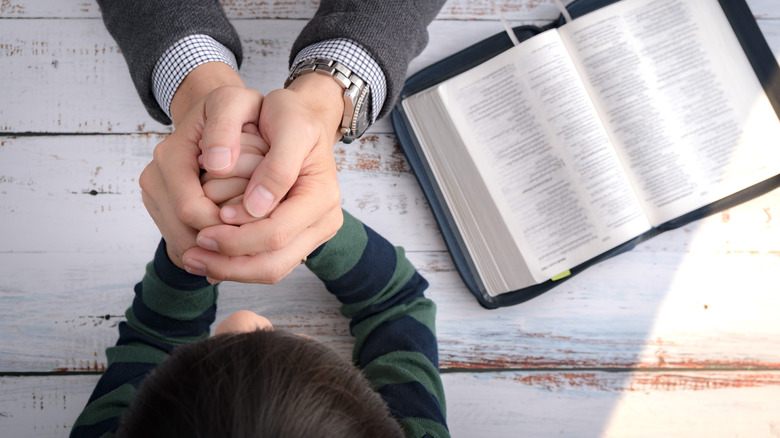 Man and child holding hands over open book