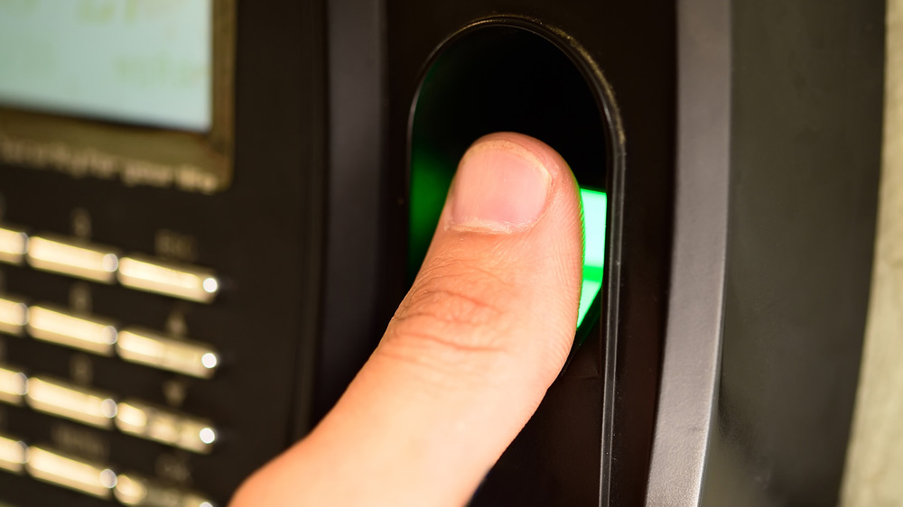 A thumb pressing against a biometric scanner