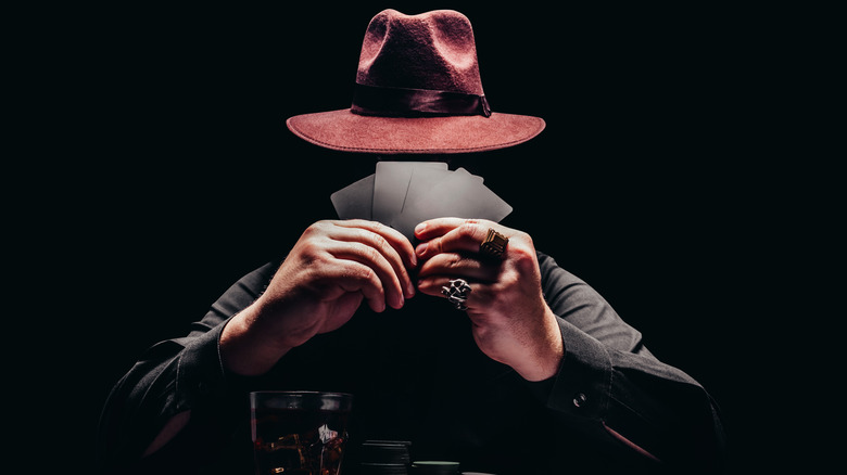 Man hat holding cards black background