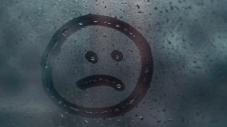 Sad face drawn on a window 