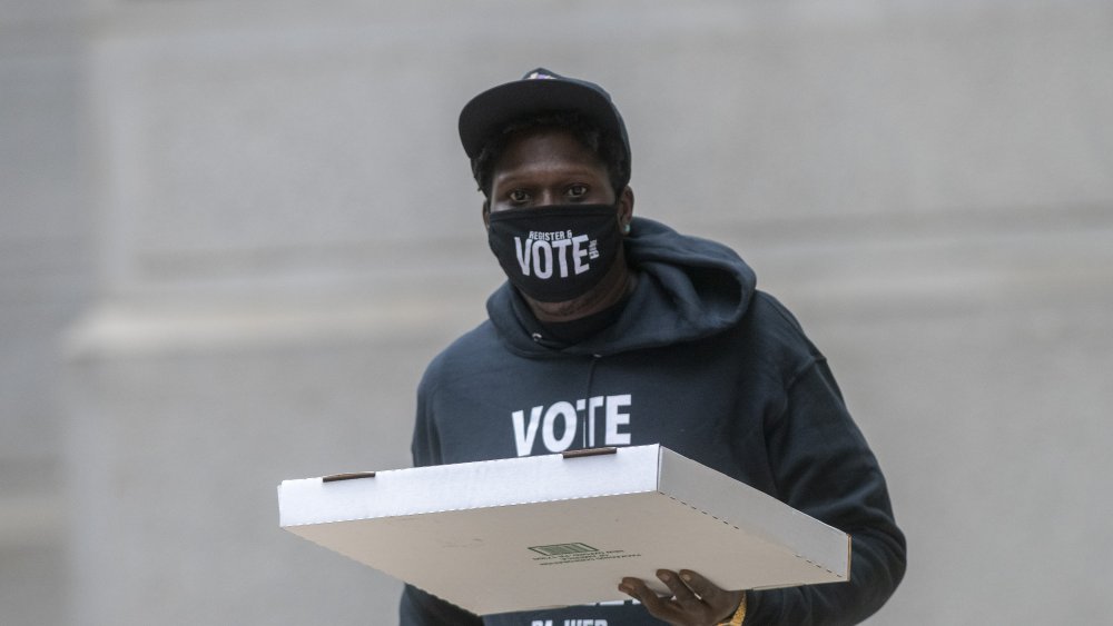 Site manager volunteer Jovaan Tarres, 30, wears a sweatshirt and face mask that read "VOTE" outside the City Hall satellite polling station on October 27, 2020 in Philadelphia, Pennsylvania. 