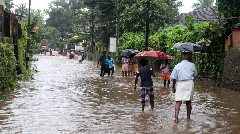 people walking through flooded street umbrellas
