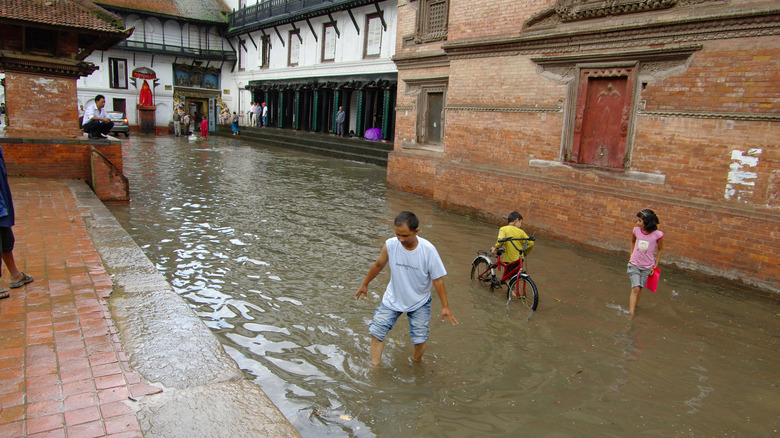 people walking through flooded street