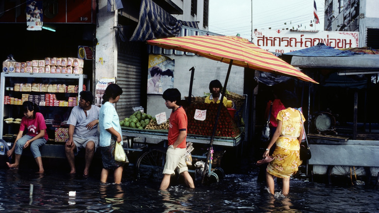 people walking through flooded streets bangkok