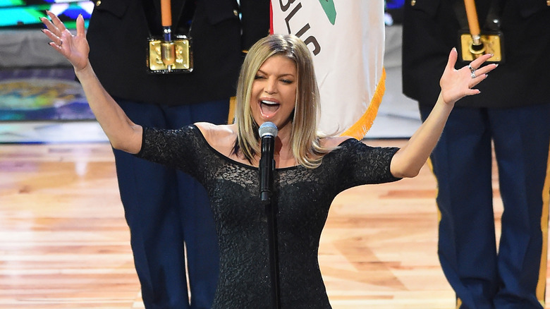 Fergie raising her hands and singing at the NBA All-Star game in 2018