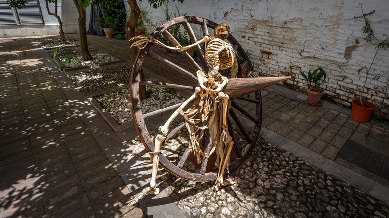 A skeleton broken on the wheel outside of a museum