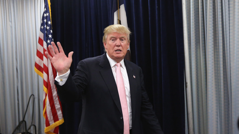 Donald Trump waving in front of stars and stripes