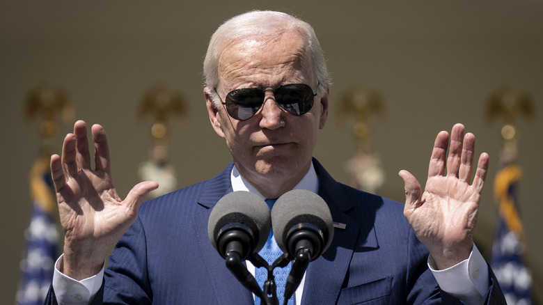 Joe Biden wearing sunglasses holding up both hands