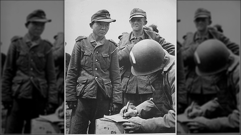 Japanese soldier wearing German uniform, speaking to American soldiers after capture on D-Day in Normandy.