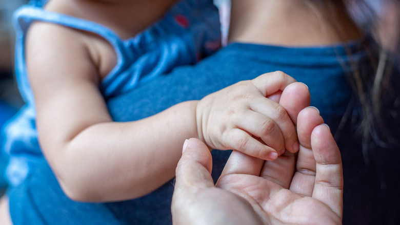 A child holding an adult's hand while being held by another adult