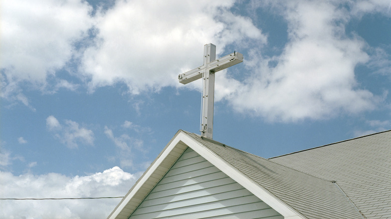 A church steeple and crucifix against a blue sky