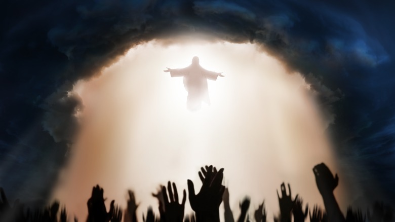 Hands raised towards Jesus in clouds