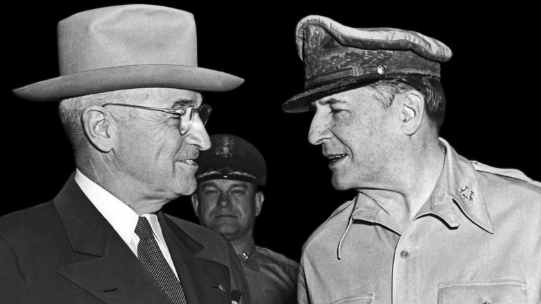 Harry Truman and Douglas MacArthur talking with man in background