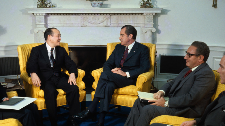 President Richard Nixon seated in the Oval Office with a Vietnamese envoy and Henry Kissinger