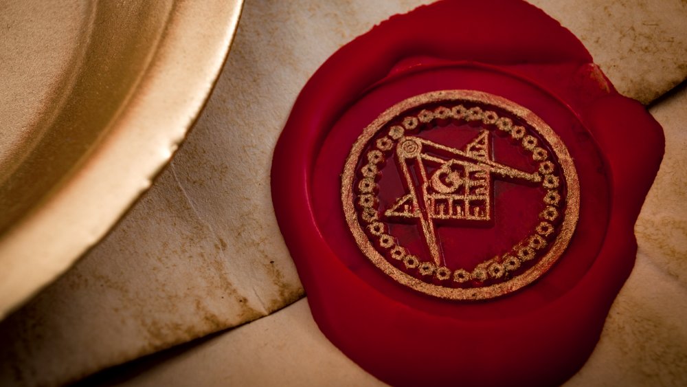 Freemason secret symbol concept with vintage letter under a candle, sealed with red wax seal with the square, the compass and the G letter in the middle, one of the most identifiable masonic symbols