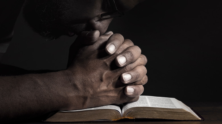 A man prays in a dimly-lit room.