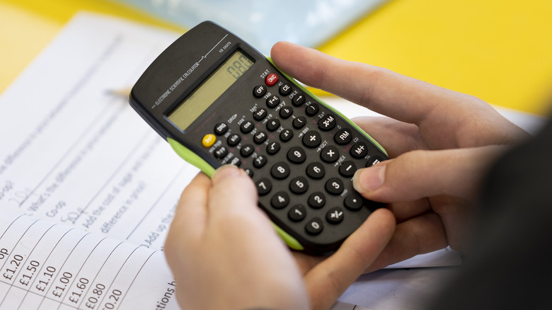 hand holding calculator over test