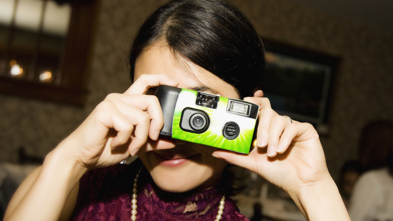 woman taking photo with disposable camera at camera