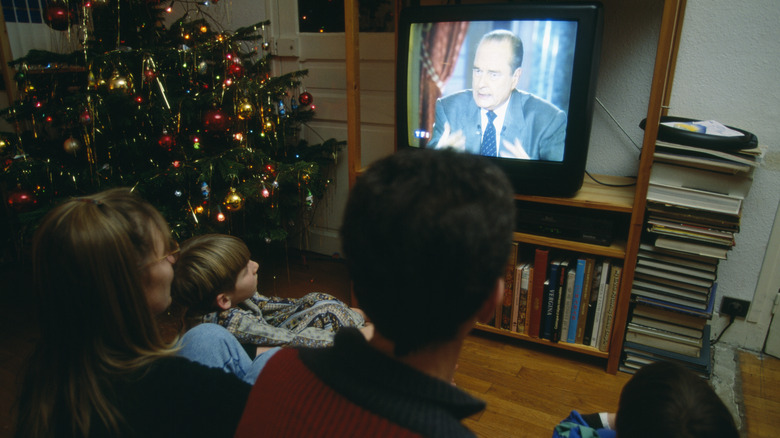 family watching tv in 1990s by christmas tree