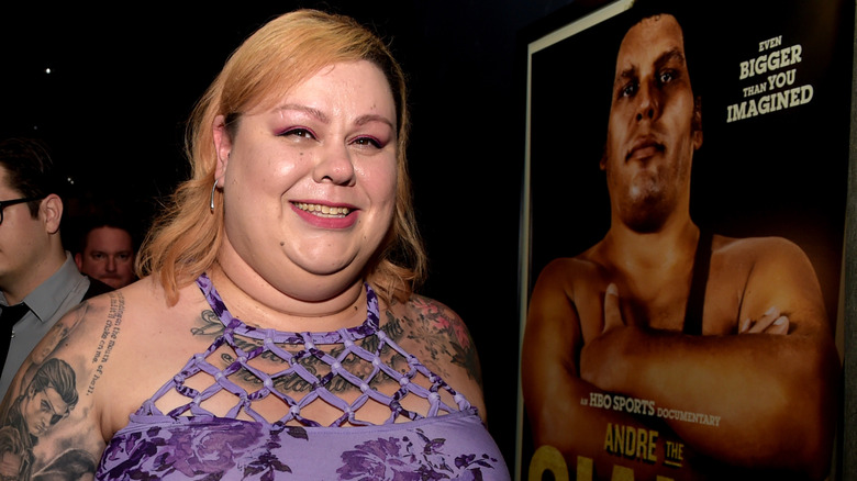 Robin Christensen-Roussimoff posing alongside a poster of Andre the Giant