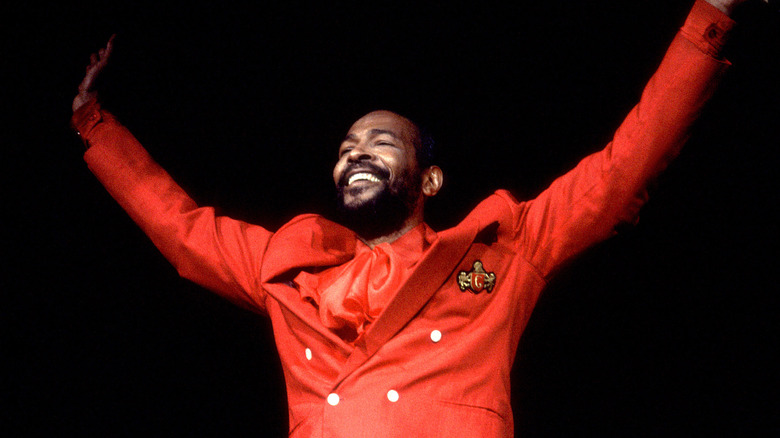 Marvin Gaye smiling arms up on stage in red suit