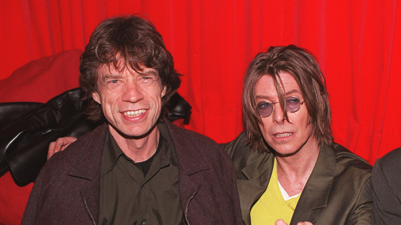 mick jagger and david bowie smiling and pointing at camera