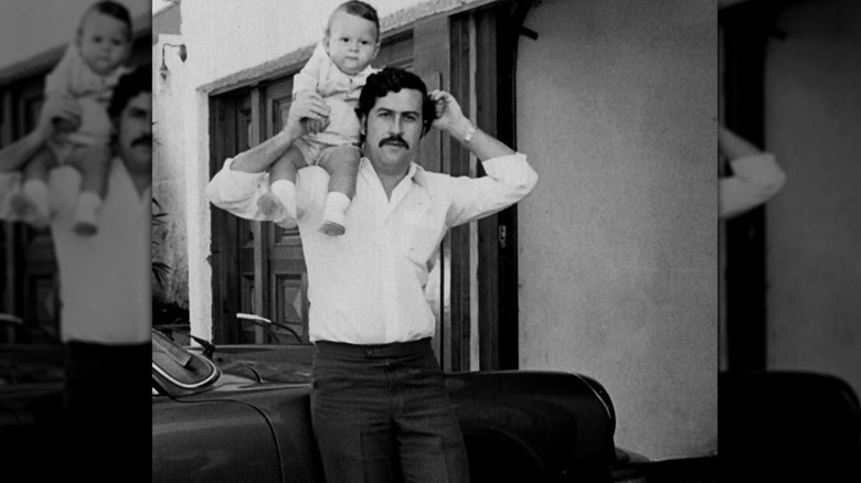 Pablo Escobar with child on shoulders by car