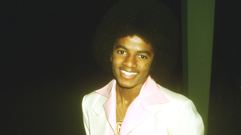 Young Michael Jackson smiling in white suit