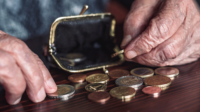 older person's hands with coins and purse