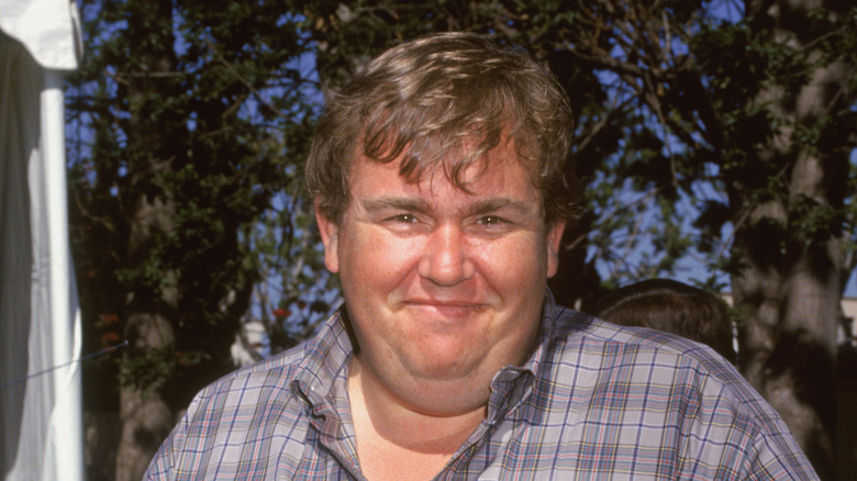 John Candy smiling in front of trees