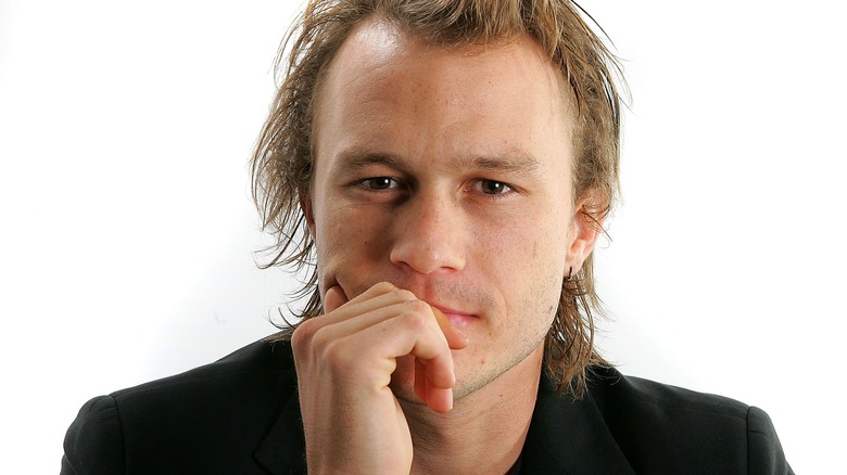 Heath Ledger black suit hand on chin white background