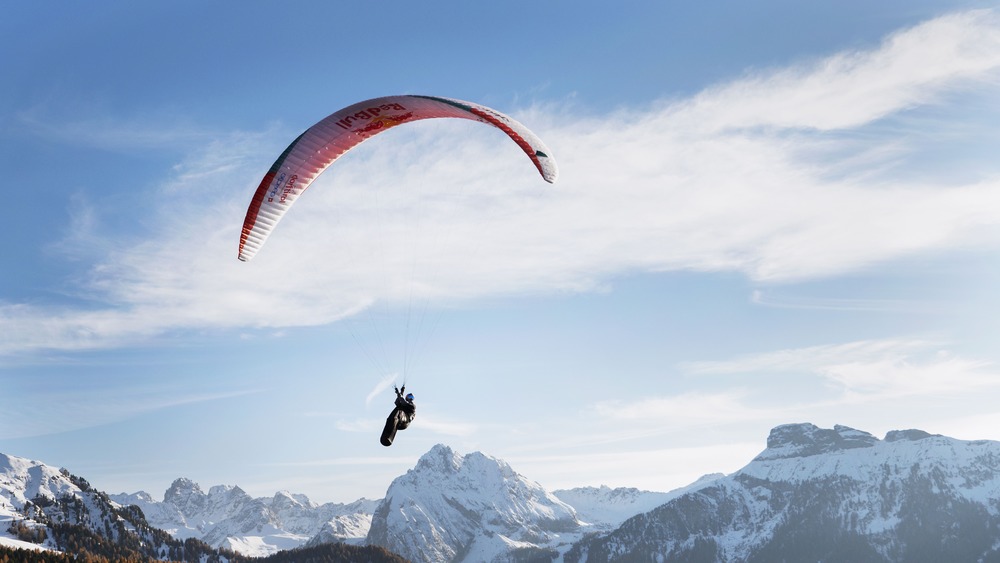 person paragliding in the mountains with blue sky