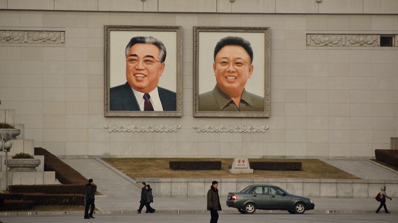 People walk past images of Kim Il-sung and Kim Jong-il