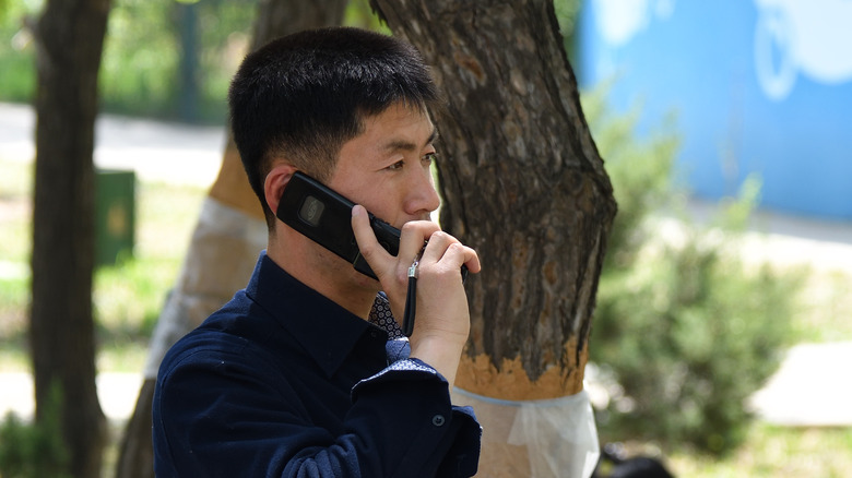 North Korean man talking on a cellphone outside