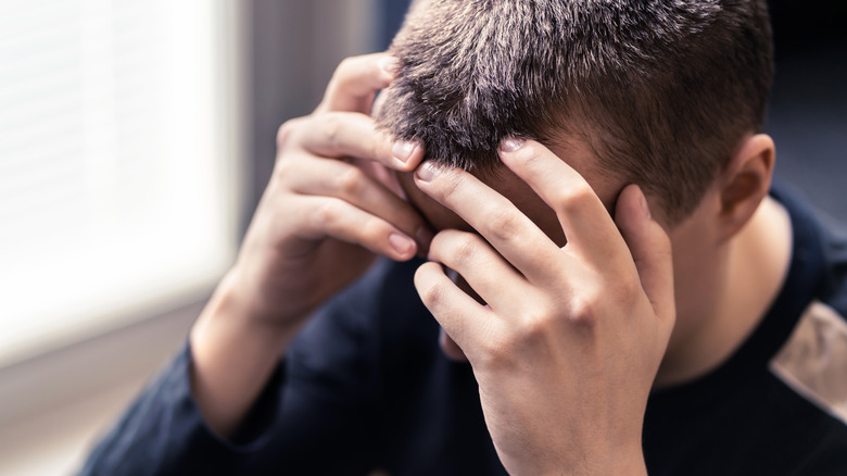 Man holding head looking despondent