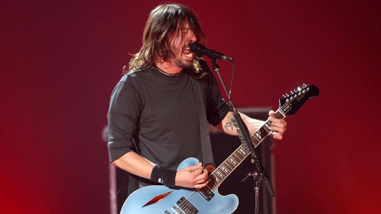 Dave Grohl playing guitar red background