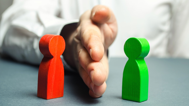 a hand in the middle between two wooden figures