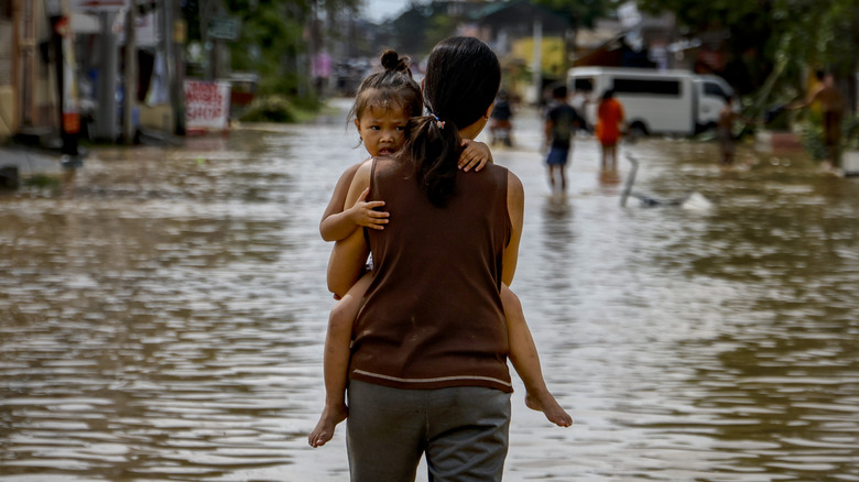 Woman carrying child through floodwaters