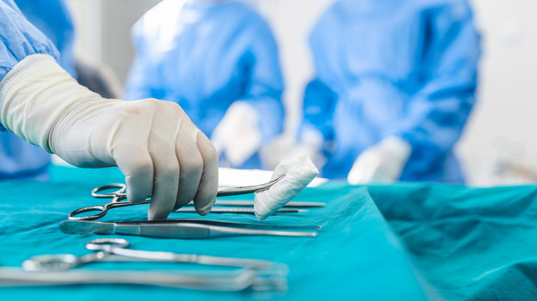 nurse grabbing surgical instrument