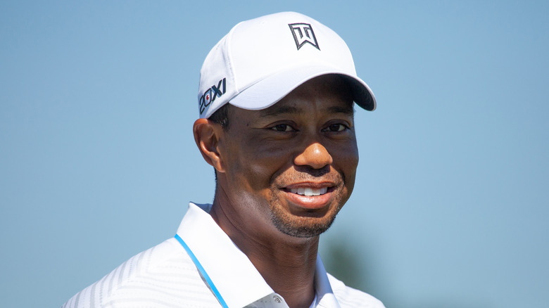 Tiger Woods in white golf gear and hat smiling in 2012