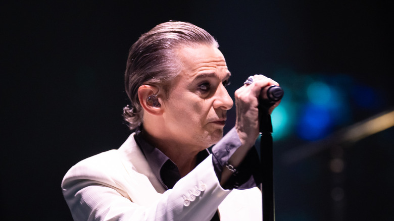 dave gahan in white suit holding mic on stage