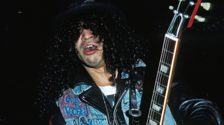 slash playing guitar with mouth gaping in the 1980s