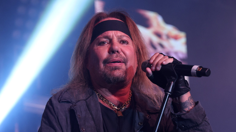 vince neil with bandanna onstage holding mic